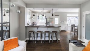 Una cocina moderna con una isla central, taburetes de bar e iluminación colgante.