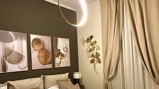 A modern bedroom with a large bed, wall art, a lamp, and curtains. - InCity Suite: Elegant Downtown Business and Urban Living in the Heart of the City (Salerno)