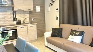 A modern kitchen with built-in appliances, a dining area with a table and chairs, and a living room with a sofa and decorative pillows. - InCity Suite: Elegant Downtown Business and Urban Living in the Heart of the City (Salerno)