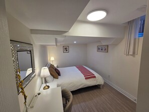 Un dormitorio con cama, mesita de noche, lámpara y espejo.