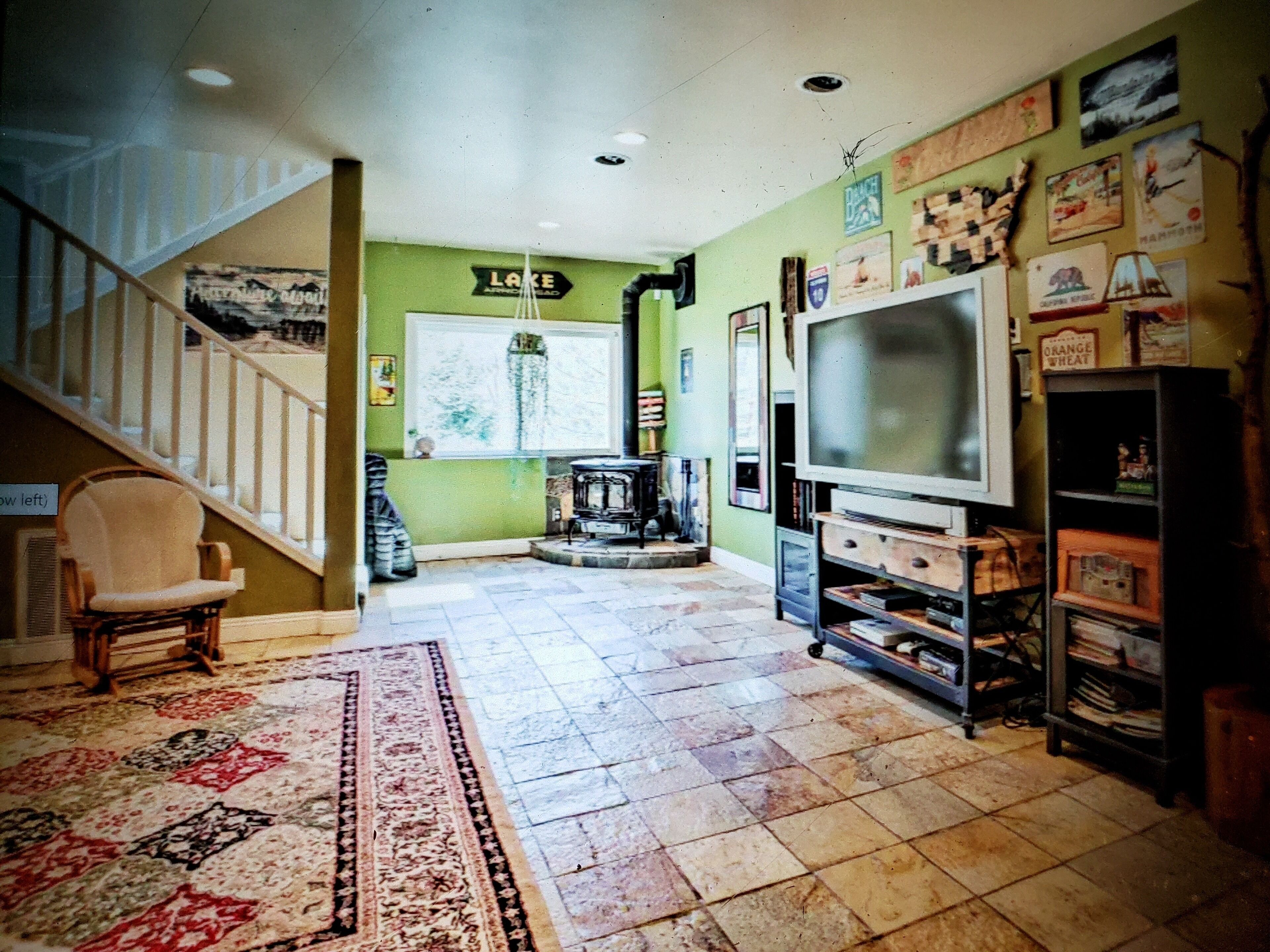 A living room with a staircase, a large TV, and a bookshelf.