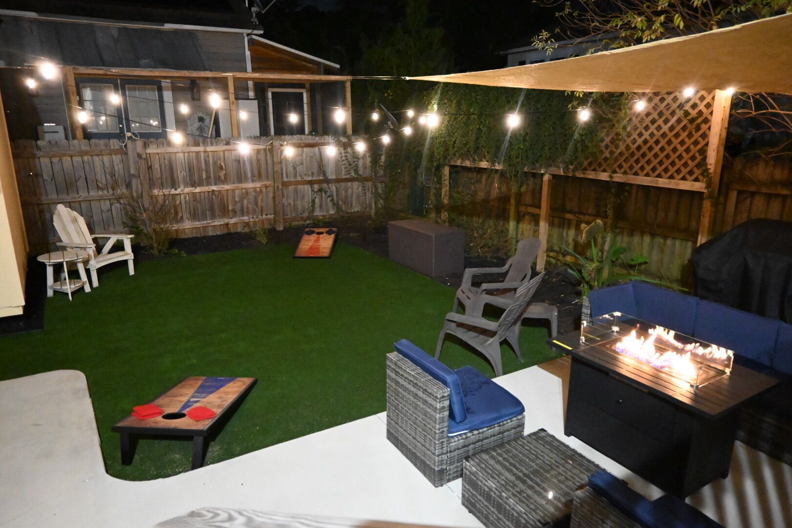 An outdoor patio area with a fire table, seating, and string lights.