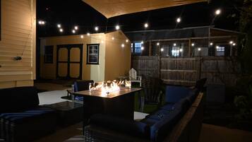 Eine Außenpatio-Terrasse mit Feuerstelle, Sitzgelegenheiten und Lichterketten.