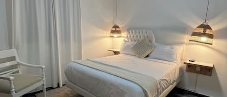 Une chambre à coucher comprenant un lit, deux tables de chevet, une chaise, un appareil de climatisation et un luminaire suspendu.