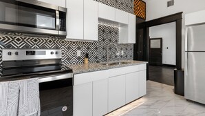 Una cocina moderna con electrodomésticos de acero inoxidable, un salpicadero con diseño y un suelo de mármol.