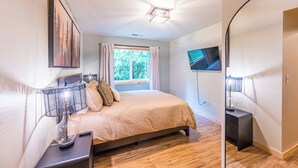 A bedroom with a bed, a TV, a heater, and a window with curtains.