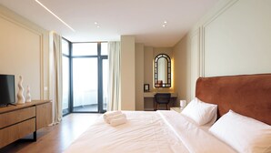 A hotel room with a large bed, a desk, a chair, a TV, and a view through a glass door. - Superb apartment with Seaview (Durrës)
