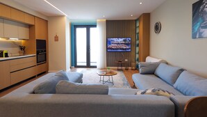 A modern living room with a grey sofa, a small round coffee table, and a TV mounted on the wall. - Superb apartment with Seaview (Durrës)