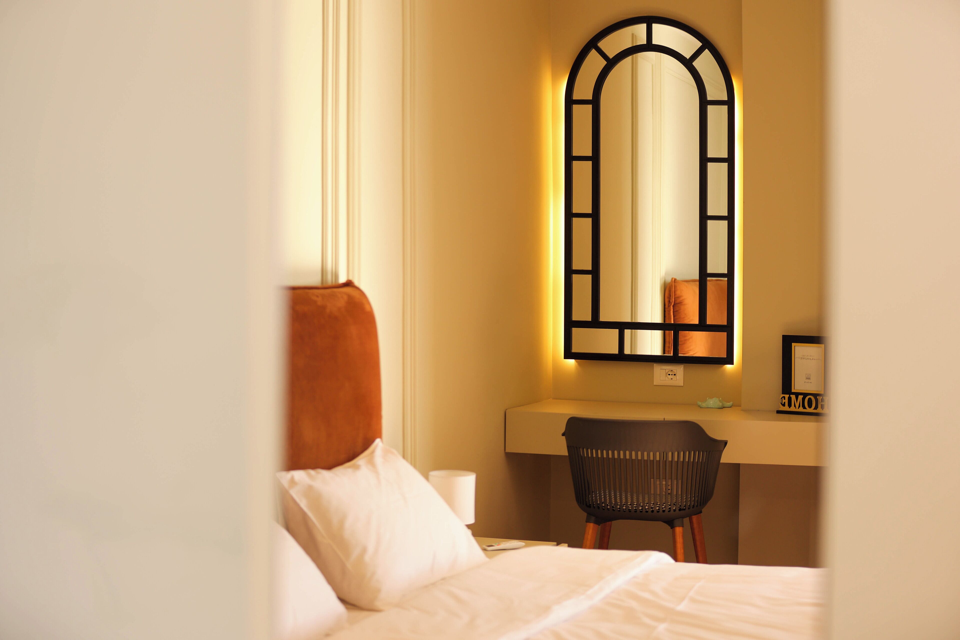 Ein Hotelzimmer mit einem Bett, einem Schreibtisch mit Stuhl, einem Spiegel und einem Nachttisch.