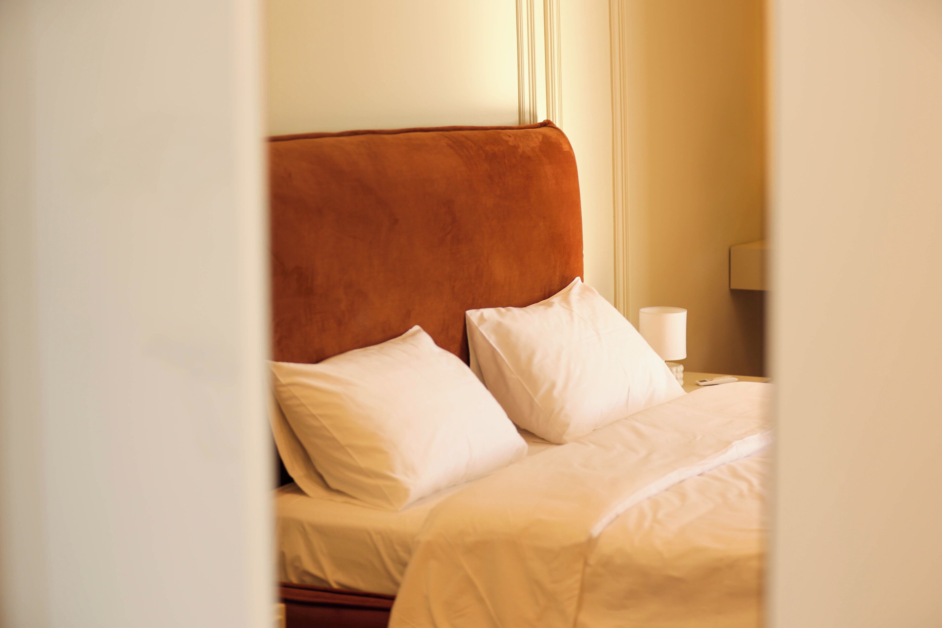 A bed with white bedding and a brown headboard in a hotel room.