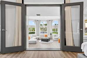 A spacious living room with a sectional sofa, a coffee table, and a view of the outdoors through large windows.