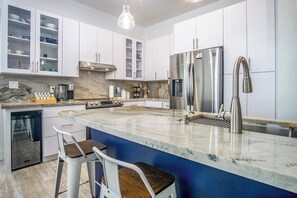 A modern kitchen with white cabinets, a stainless steel refrigerator, a built-in oven, and a marble countertop. - Duck Key Bimini Retreat 3 bedroom 2 bath home with swim spa (Duck Key)