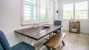 A dining area with a wooden table, benches, and a decorative shelf with items. - Duck Key Bimini Retreat 3 bedroom 2 bath home with swim spa (Duck Key)