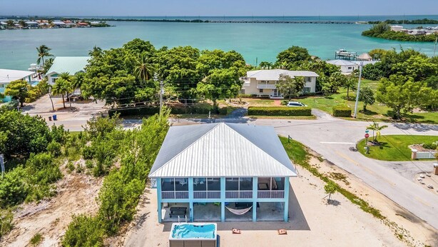 A coastal property with a pool, a large building with a blue roof, and a view of the sea. - Duck Key Bimini Retreat 3 bedroom 2 bath home with swim spa (Duck Key)