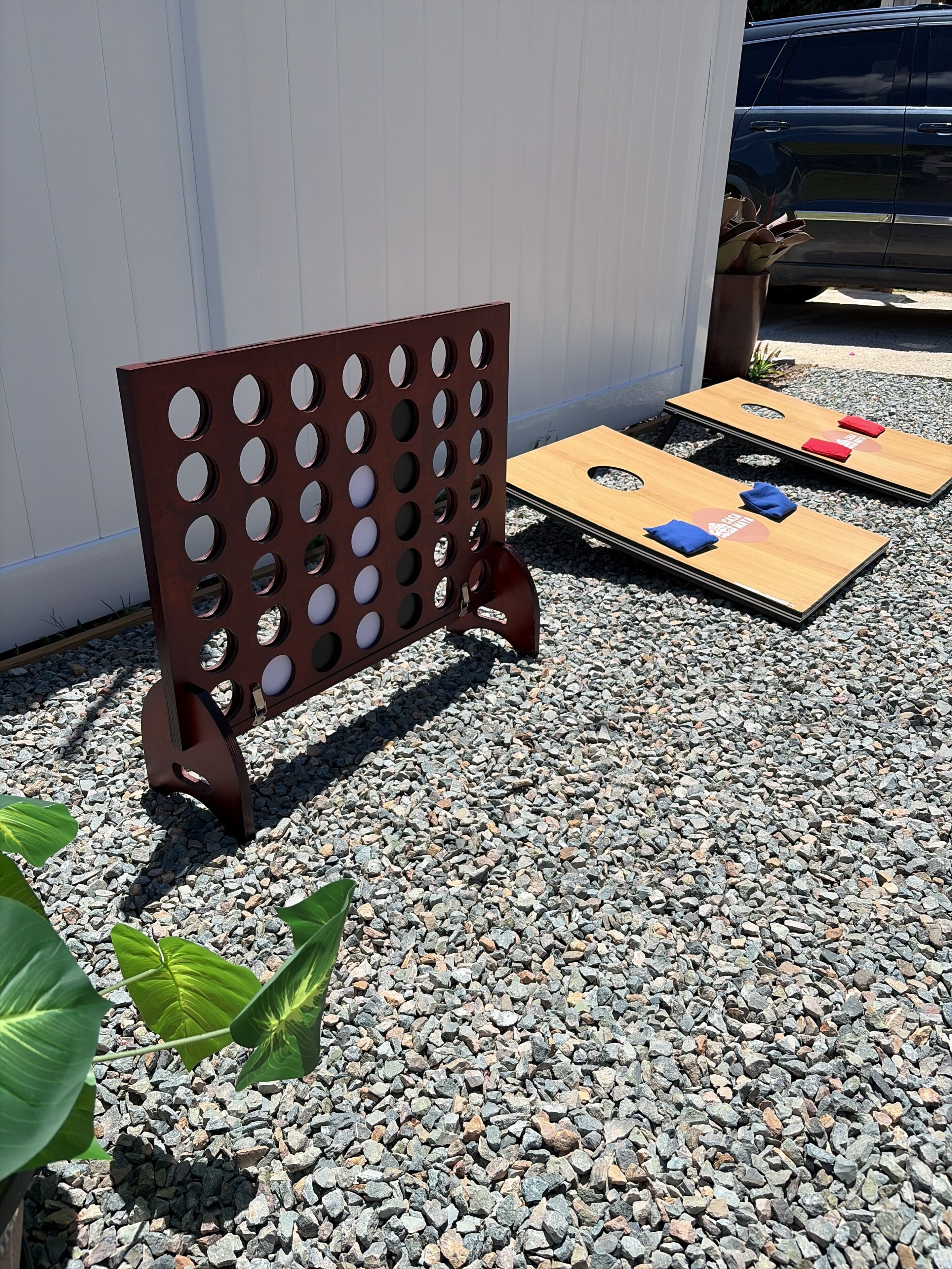 A metal board with circular cutouts, two wooden boards with red and blue cushions, and a gravel ground.