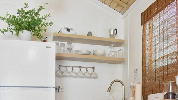 Een keuken met witte kasten, een houten plafond, een eettafel met een dienblad koekjes en een bloempot.