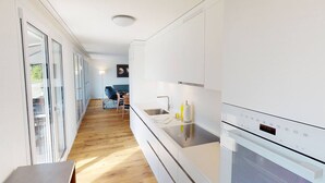 A modern kitchen with white cabinets, a stainless steel sink, and a built-in oven.