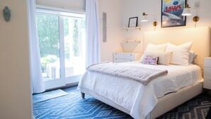 Une chambre à coucher avec un lit, une fenêtre avec des rideaux, une affiche accrochée au mur, des lampes de chevet et une table de chevet.