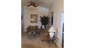 A living room with a ceiling fan, two couches, a coffee table, and a lamp.
