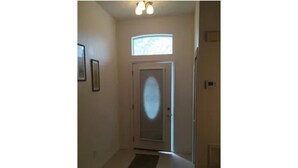 A hallway with a door, a small window, and a rug.