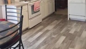 A kitchen with white cabinets, a stove, and a dining table with chairs.