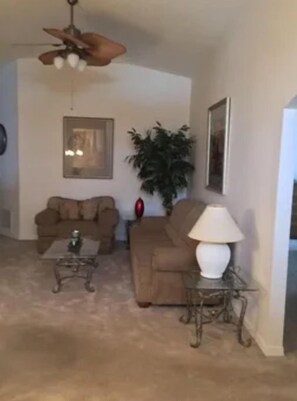 Ein Wohnzimmer mit Deckenventilator, zwei Sofas, einem Couchtisch und einer Lampe.