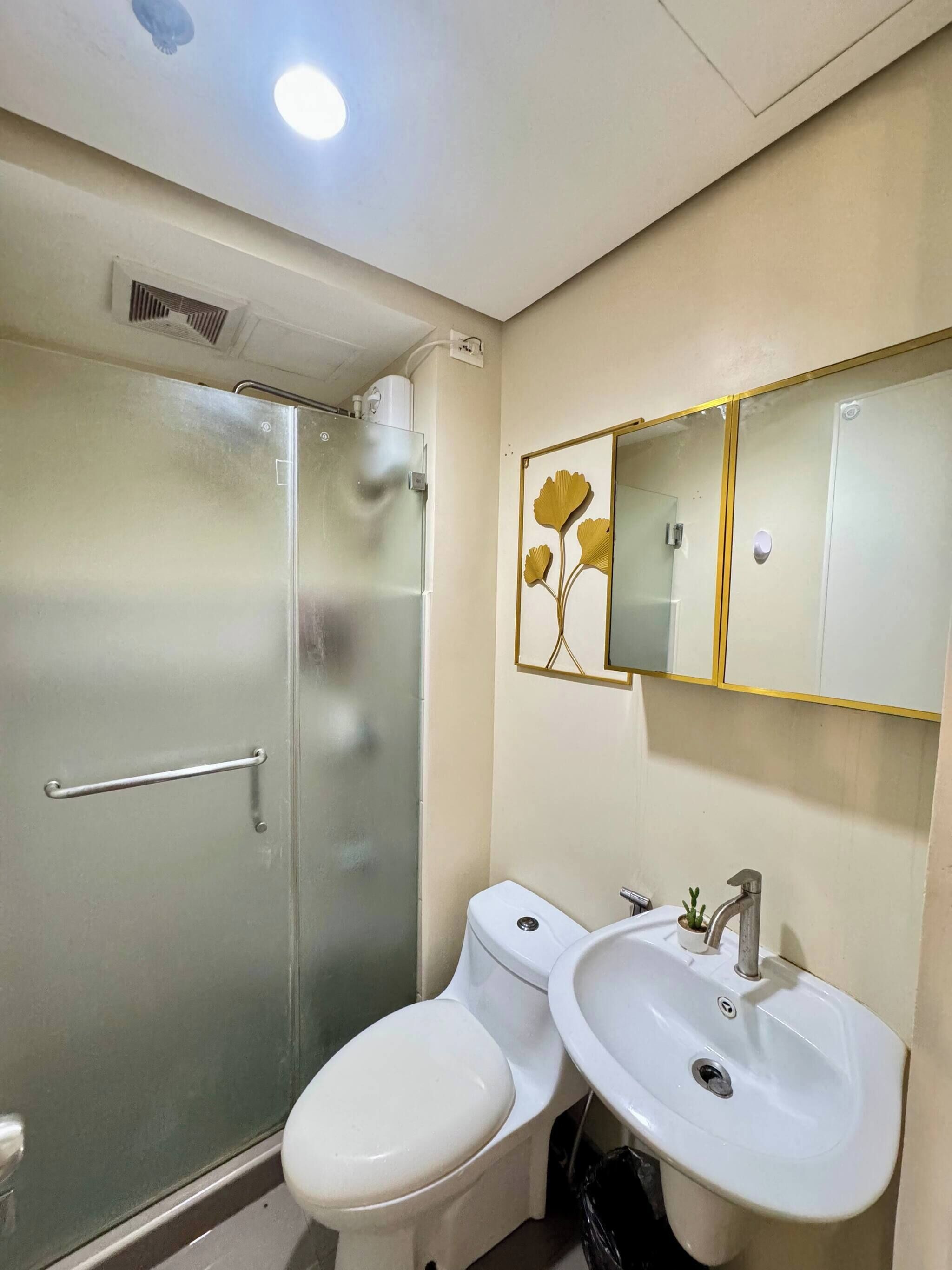 Un baño con cabina de ducha de vidrio, inodoro y lavabo con espejo.
