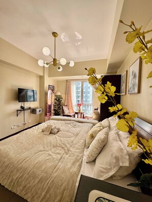 Een hotelkamer met een groot bed, een televisie, een nachtkastje en een raam met gordijnen.