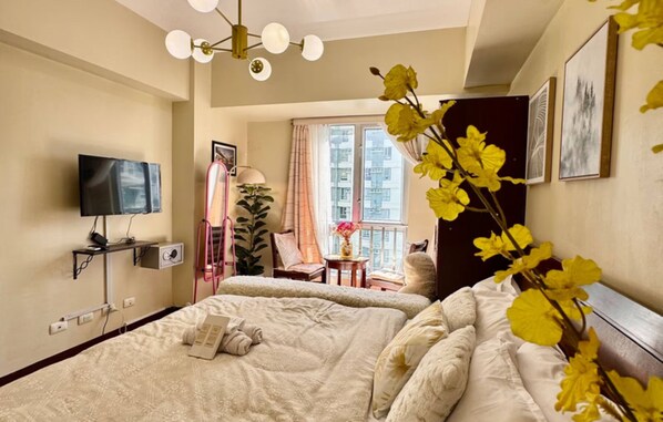 Een hotelkamer met twee bedden, een televisie, een raam met gordijnen en een plant.