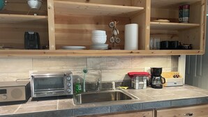Uma cozinha com armários de madeira, micro-ondas embutido, cafeteira e pia.