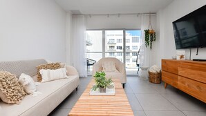 A modern living room with a sofa, a wooden coffee table with a plant, a TV, and a wooden cabinet.