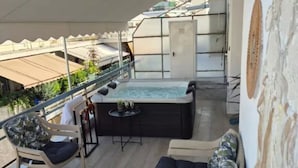 An outdoor deck with a hot tub, seating area, and a view of the cityscape. - Jacuzzi Penthouse at Gazi nights (Athina)