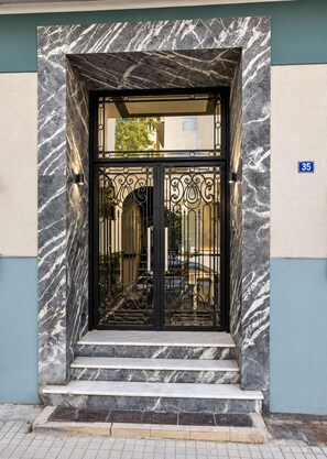 A black metal gate with intricate designs, set within a marble facade, and a blue sign with the number 35. - Jacuzzi Penthouse at Gazi nights (Athina)