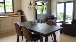 Una cocina moderna con comedor, ventanas amplias y vistas a zonas verdes.