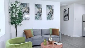 Una sala moderna con un sofá gris, un sillón verde y una mesa de centro con objetos decorativos.
