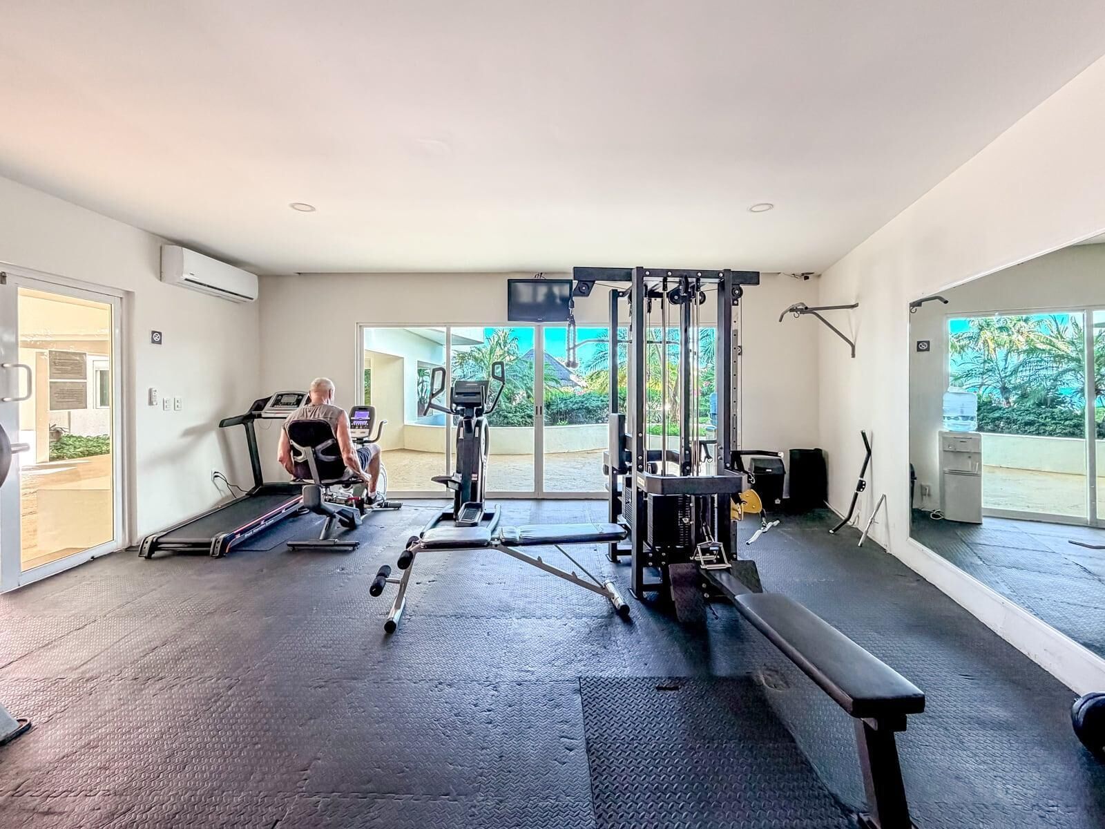 Ein Fitnessstudio mit Cardiogeräten, Gewährleistungsausrüstung und einer Bank.