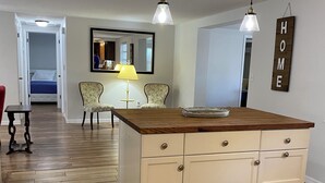 A kitchen with a wooden island, two pendant lights, a mirror, and a 'HOME' sign on the wall. - Family Getaway Near Beaches, Sleeps 8 (New Port Richey)