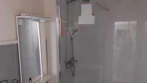 A bathroom with a sink, mirror, shower, and tiled walls. - T2 in the sun (Marseille)