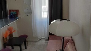 A small, well-lit room with a desk, chair, and a sofa with a lamp. - T2 in the sun (Marseille)