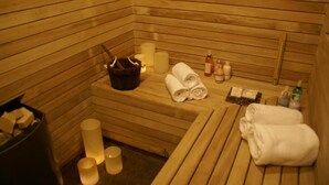 Una sauna de madera con bancos, velas, toallas y botellas de aceites y lociones.