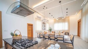 Una cocina moderna con una isla central, estufa integrada y comedor con sillas y una mesa.
