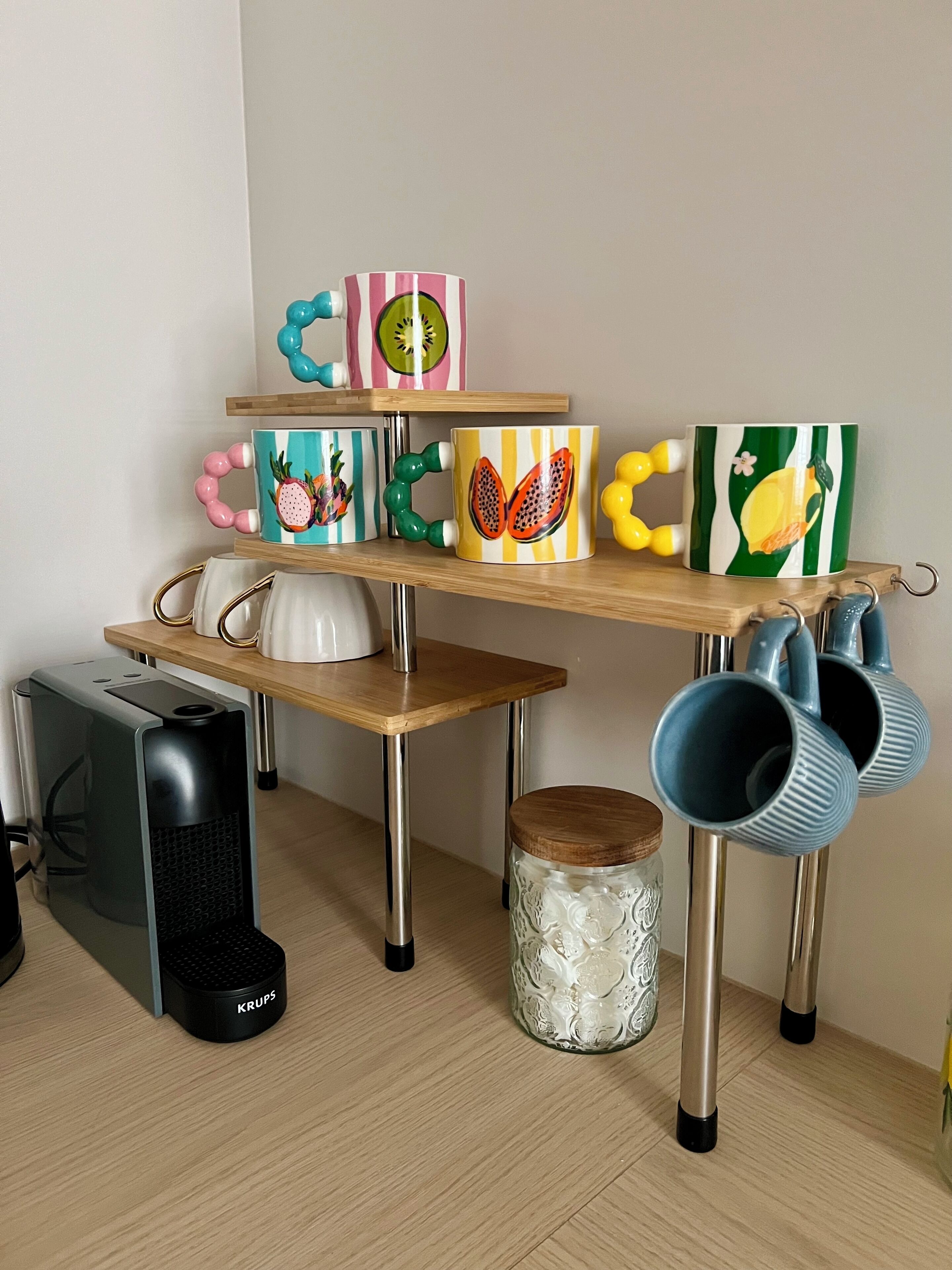 Un área de cocina con una mesa de madera, una tetera, una cafetera y una máquina de café Krups.