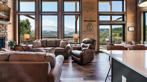 A spacious living room with large windows, a fireplace, and a dining area with outdoor seating.