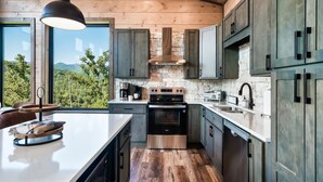 A modern kitchen with a large island, stainless steel appliances, and wooden flooring.