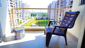 Un balcon avec une chaise et un panier, donnant sur un quartier résidentiel avec de grands immeubles.