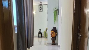 Un couloir avec un tapis, une statue de Bouddha et un luminaire au plafond.
