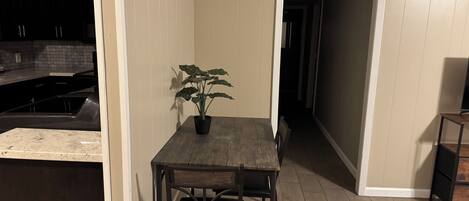 A kitchen with a dining table and chairs, a potted plant, and a TV on a stand.
