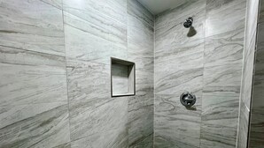 Una ducha con un espejo rectangular y un cabezal de ducha de mano.