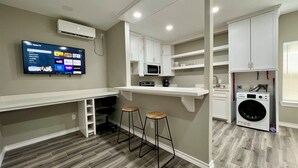 Una cocina compacta con televisión integrada, lavadora y microondas.