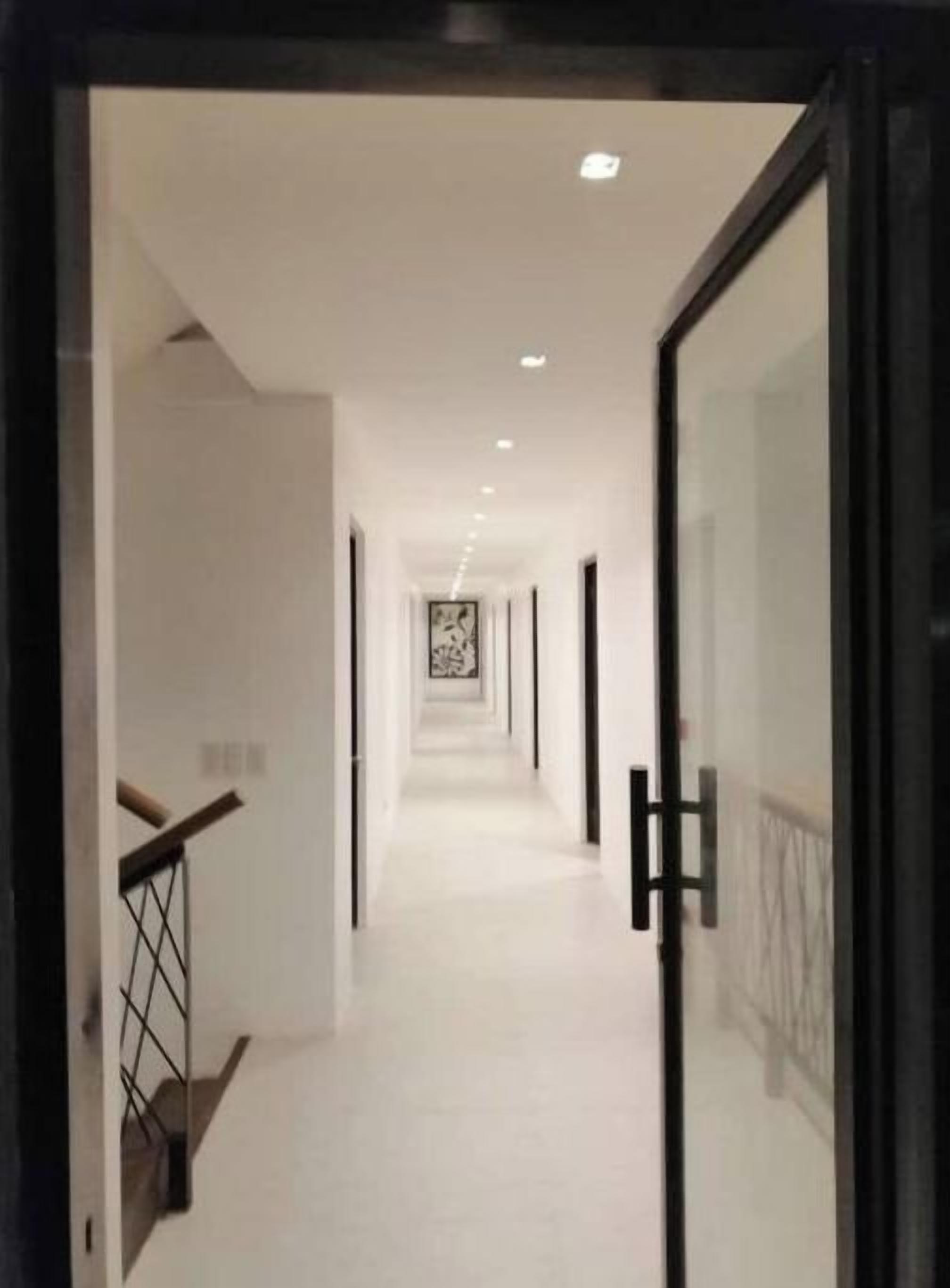 A corridor with a staircase on the left and a glass door on the right.